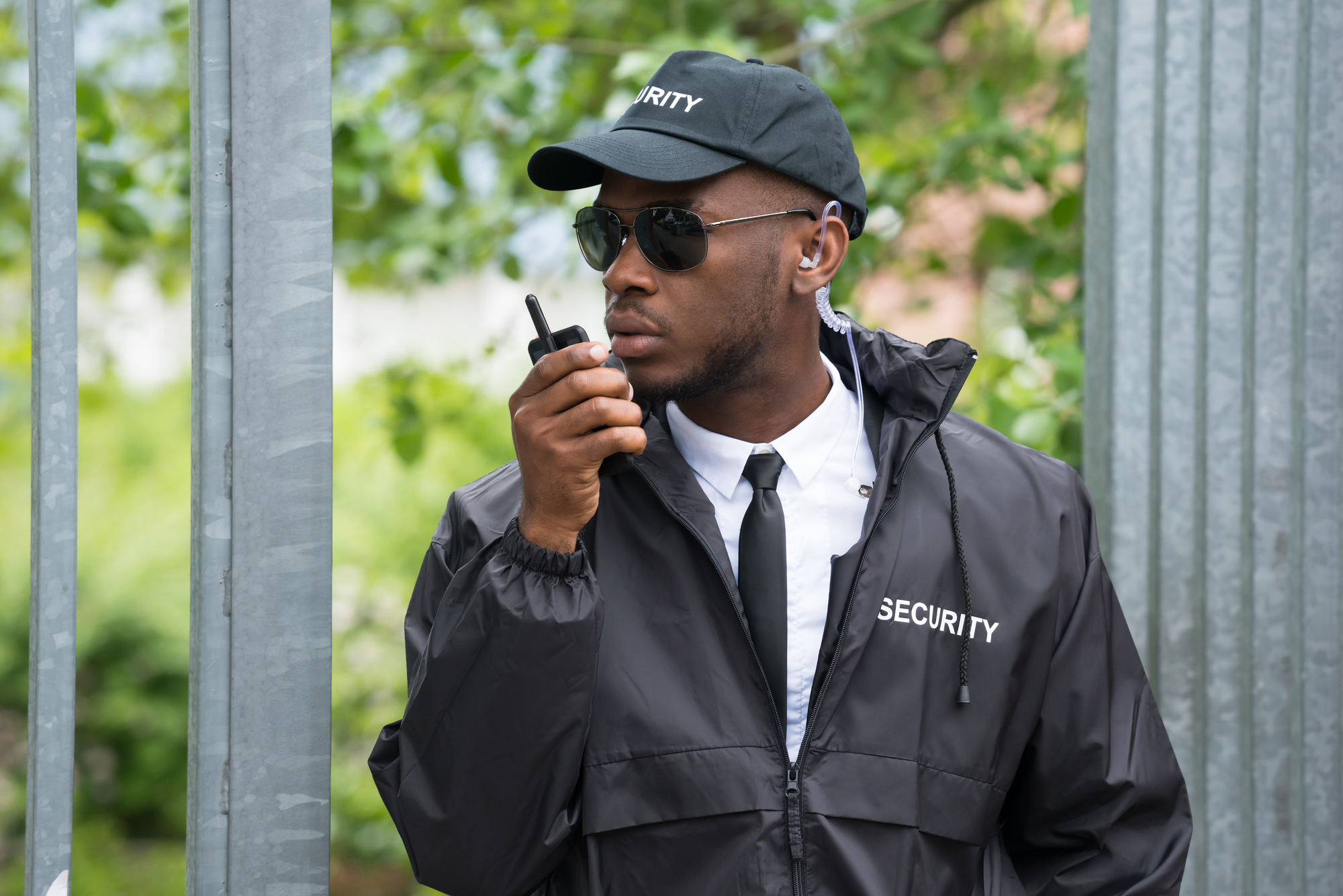 Young Male Security Guard In Black Uniform Using Walkie-Talkie