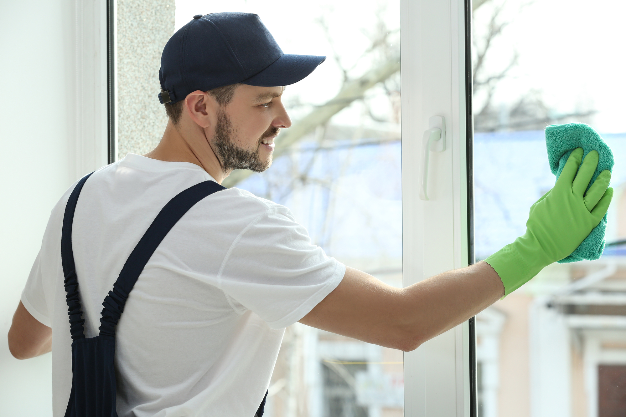 Young man cleaning window in office